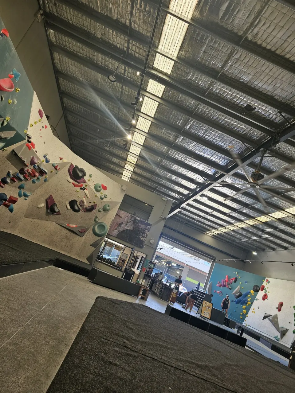 Matted bouldering hall under skylights, looking towards the entrance