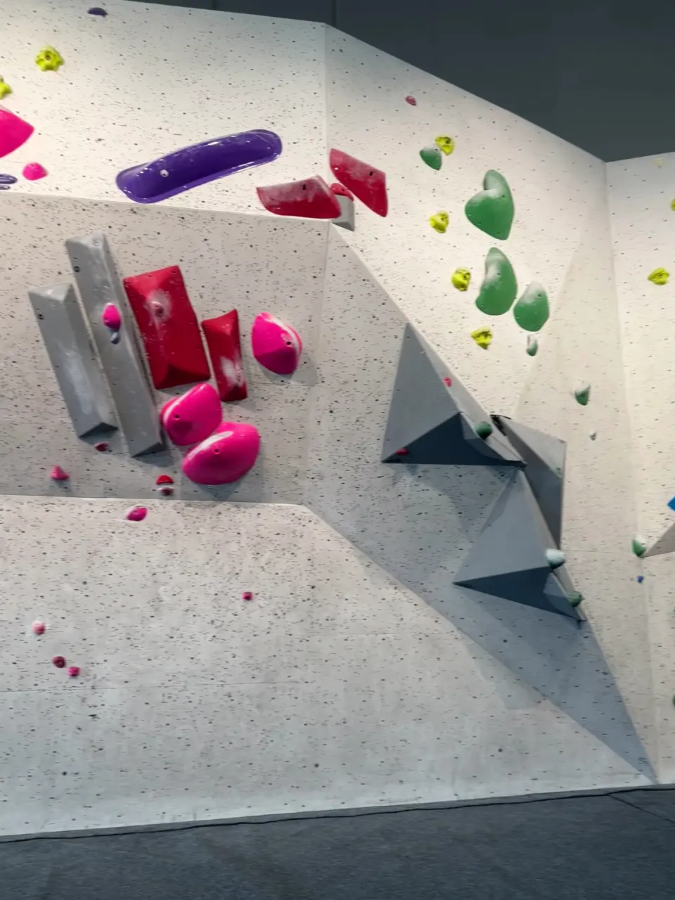 White wall with grey volumes and pink and purple holds