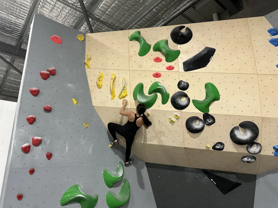 Climber on a plywood wall with green holds