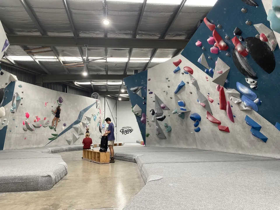 Bouldering hall with grey and navy walls above grey crash mats