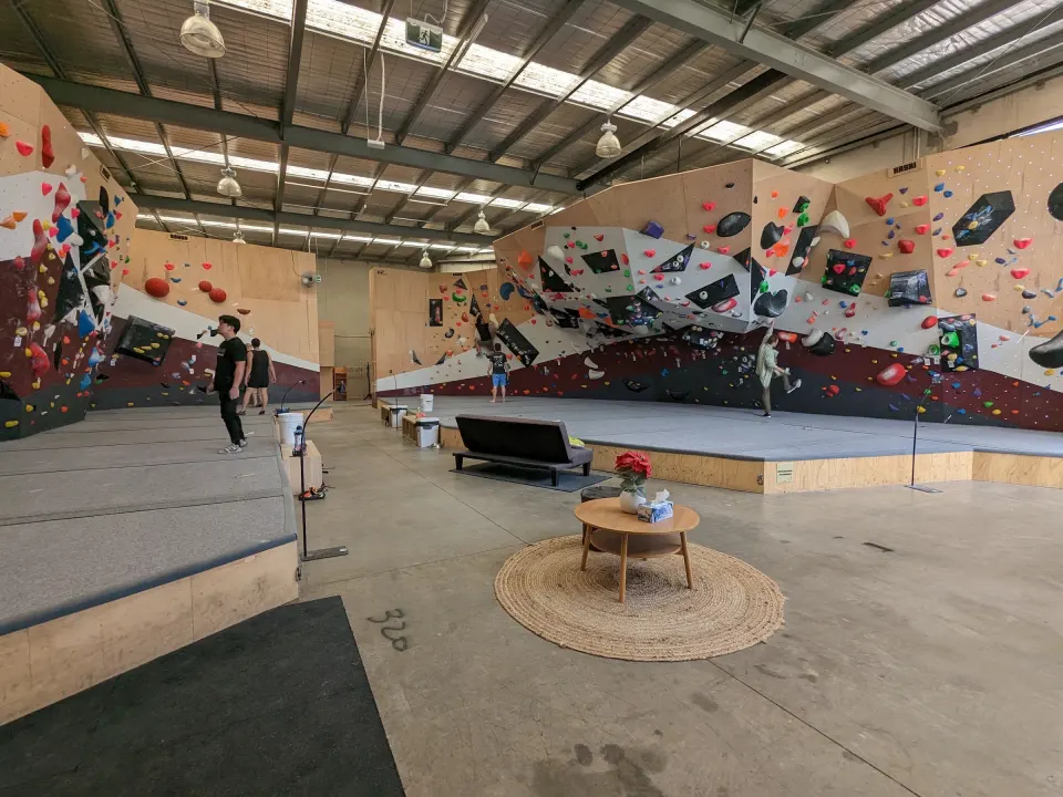 Wide view of the bouldering hall with padded floors and the lounge area