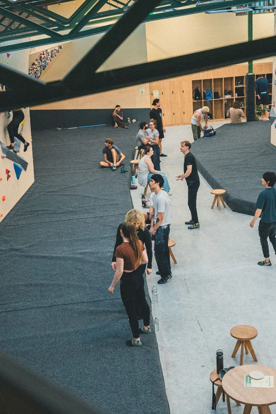Climbers resting on the matted floor between the bouldering walls, seen from above