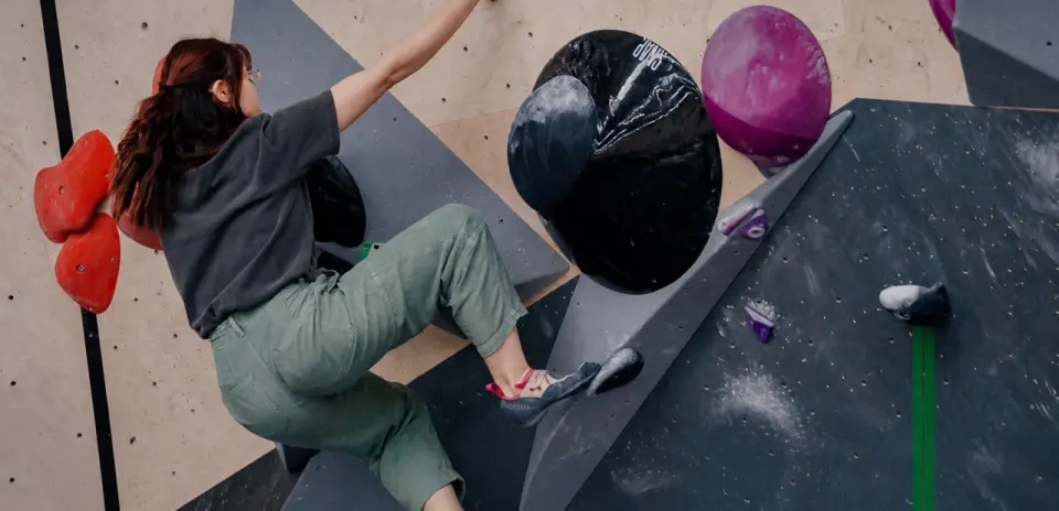 Climber stepping onto a large black volume on a steep problem