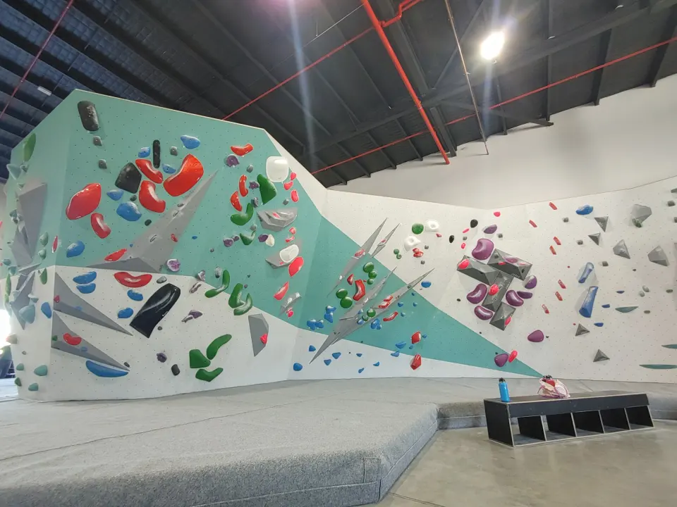 Teal and white bouldering walls above deep grey matting