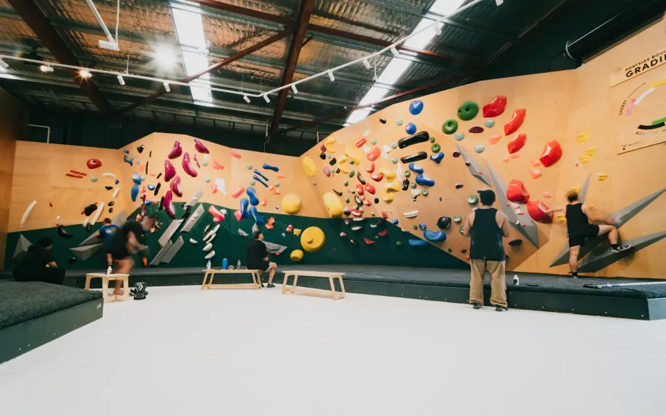 Long plywood bouldering wall with a green base above the matting