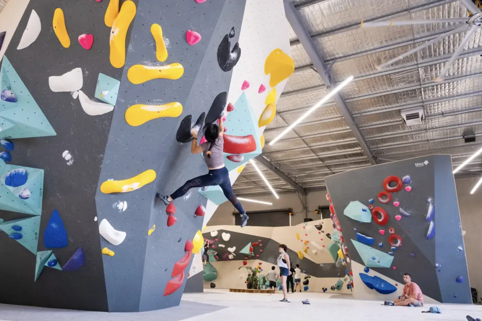 Climber on a grey wall with yellow holds, the main hall behind