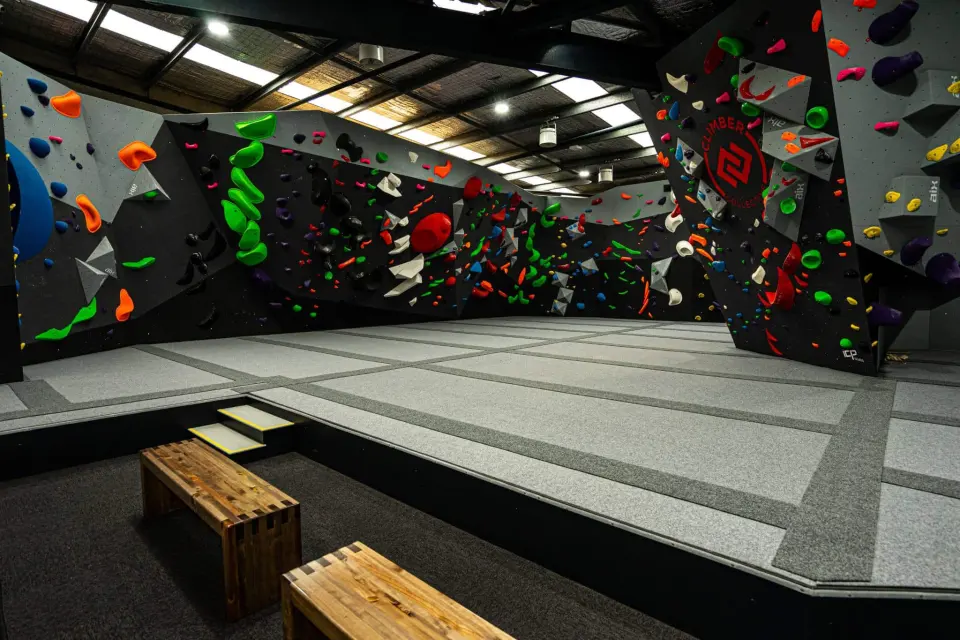 Grey bouldering walls covered in colourful holds above grey matting