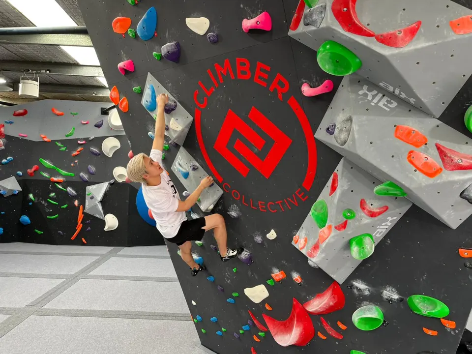 Climber on the wall with the large red Climber Collective logo