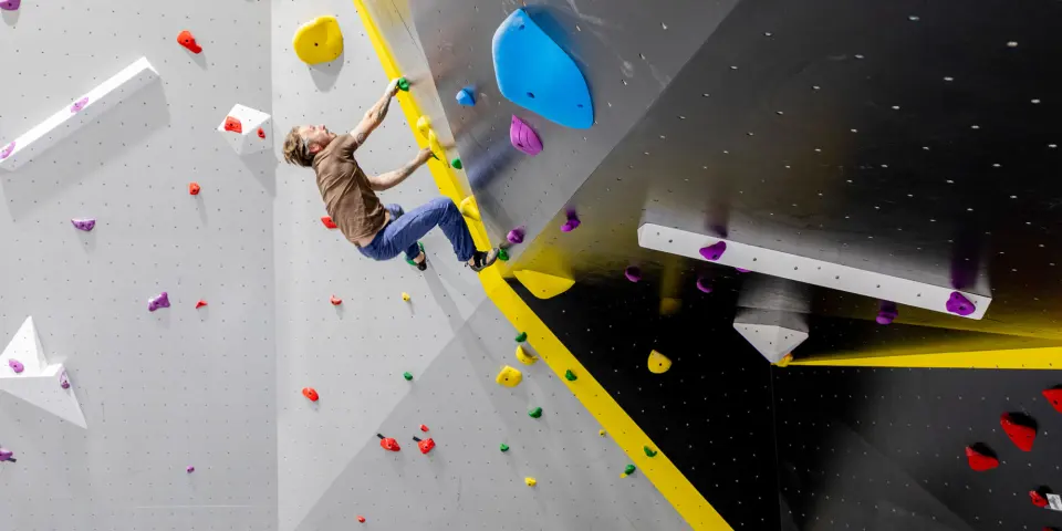 Climber moving round the arête between grey and black walls