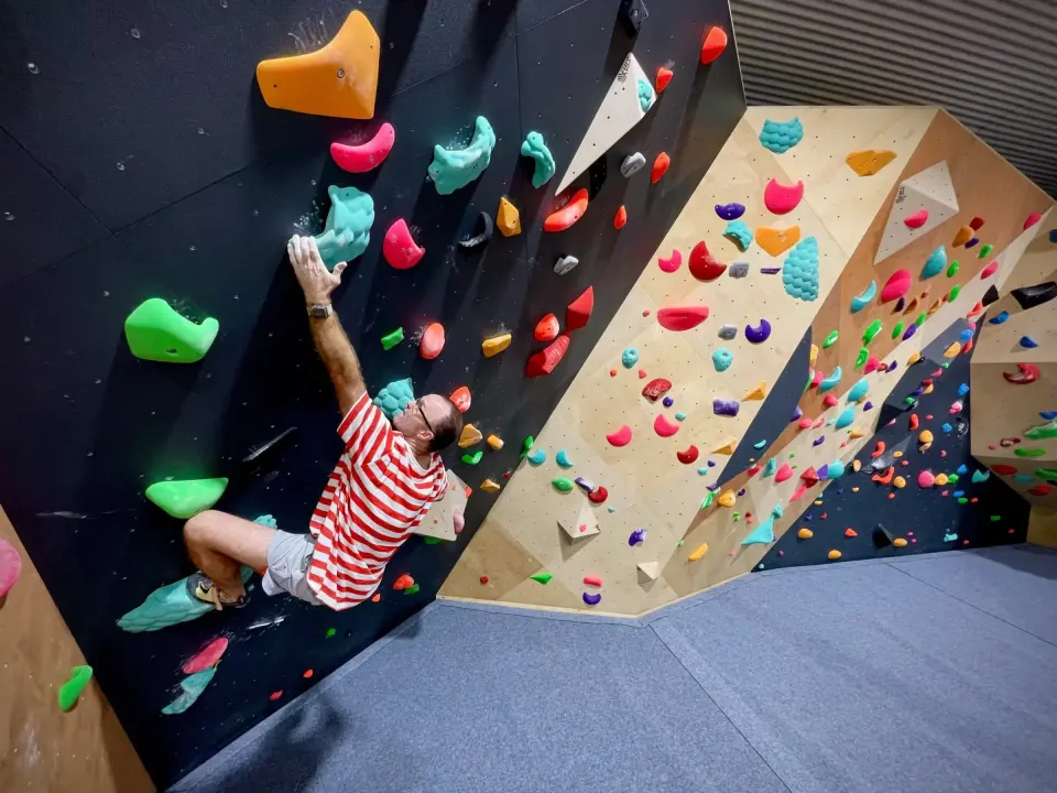 Climber reaching across the steep black wall