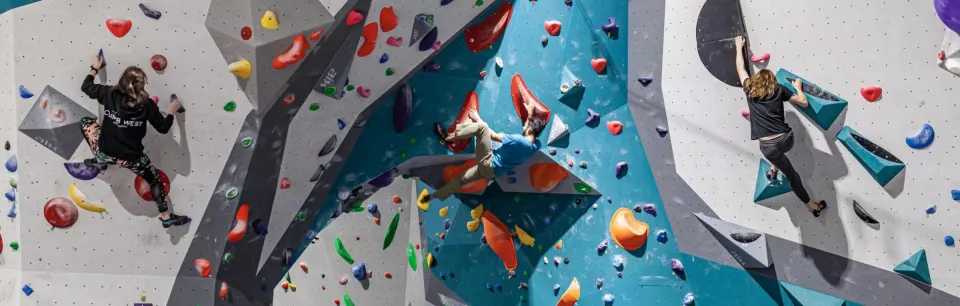 Climbers on the teal and grey bouldering walls