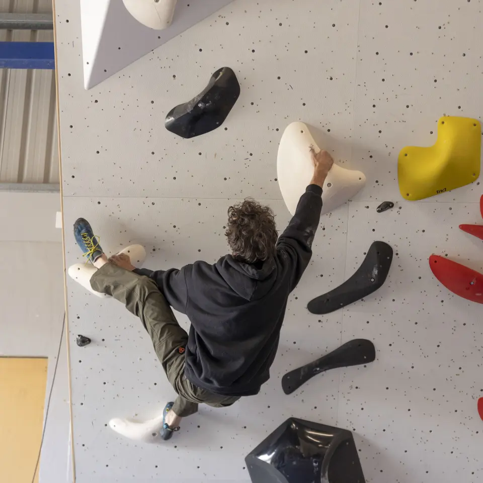 Climber reaching between large holds on a vertical wall