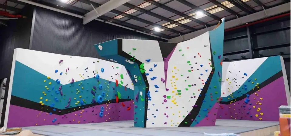 The bouldering hall's teal, purple and white walls around a central pillar