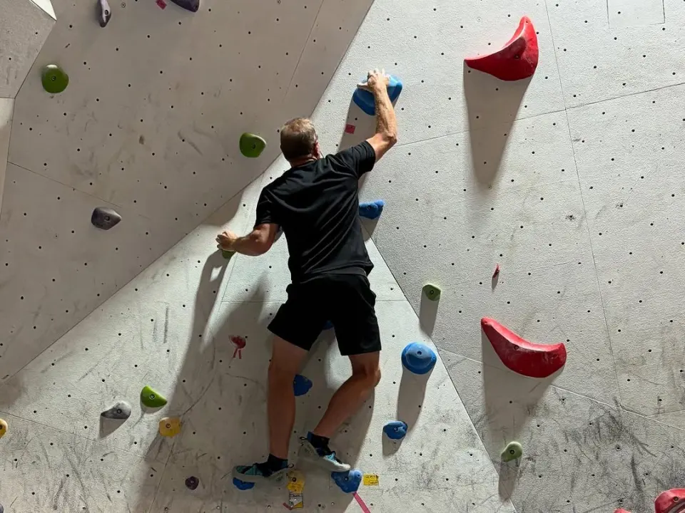 Climber on a white wall with red volumes