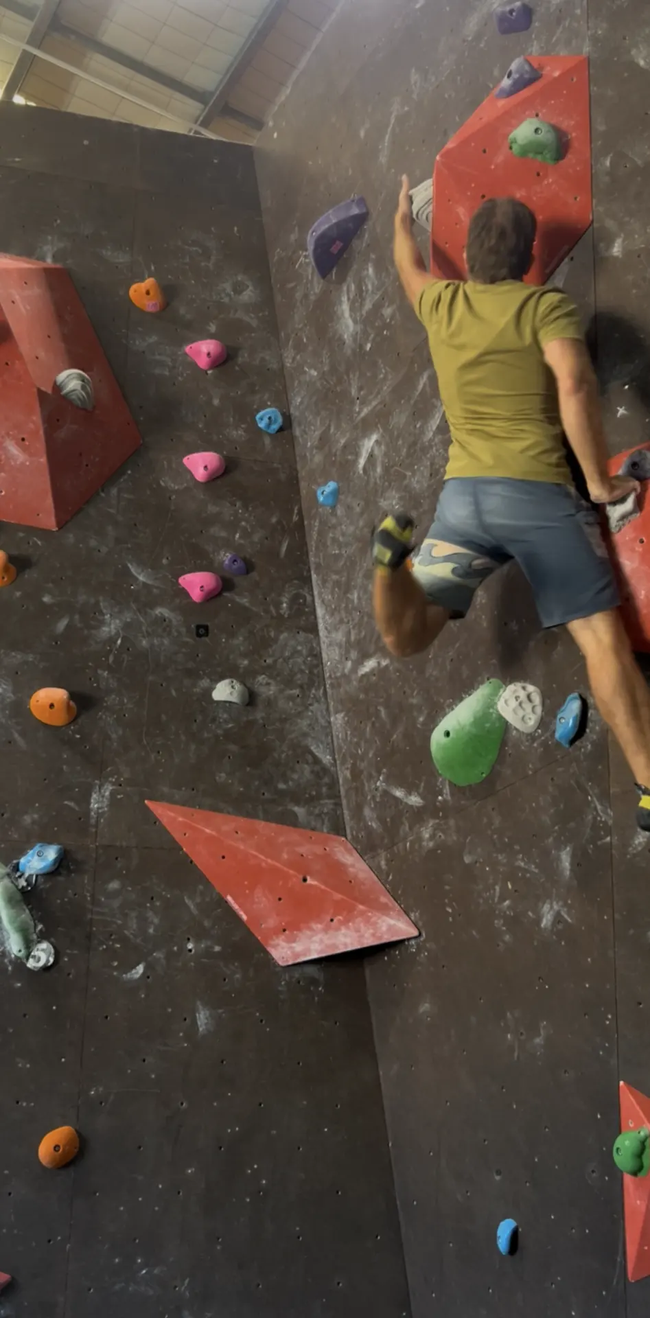 Climber on the dark wall reaching for a red volume