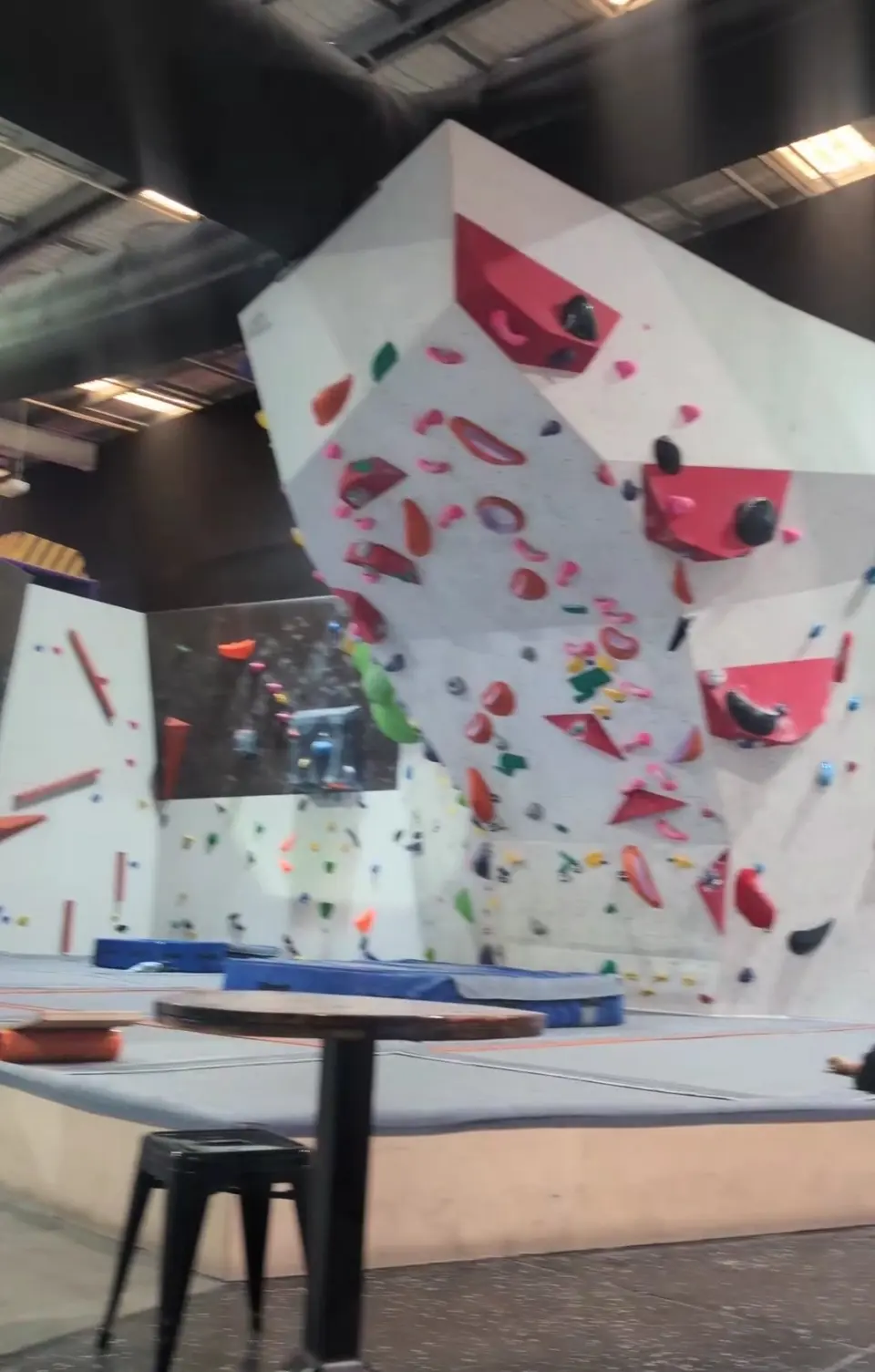 White bouldering walls with red volumes above blue matting