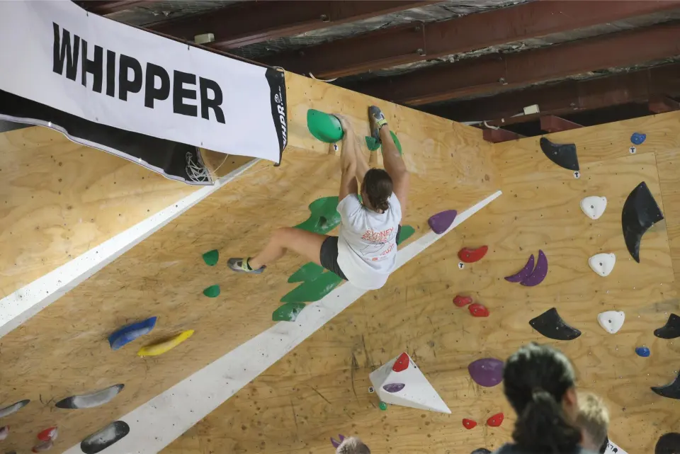 Climber pulling through an overhang on green holds