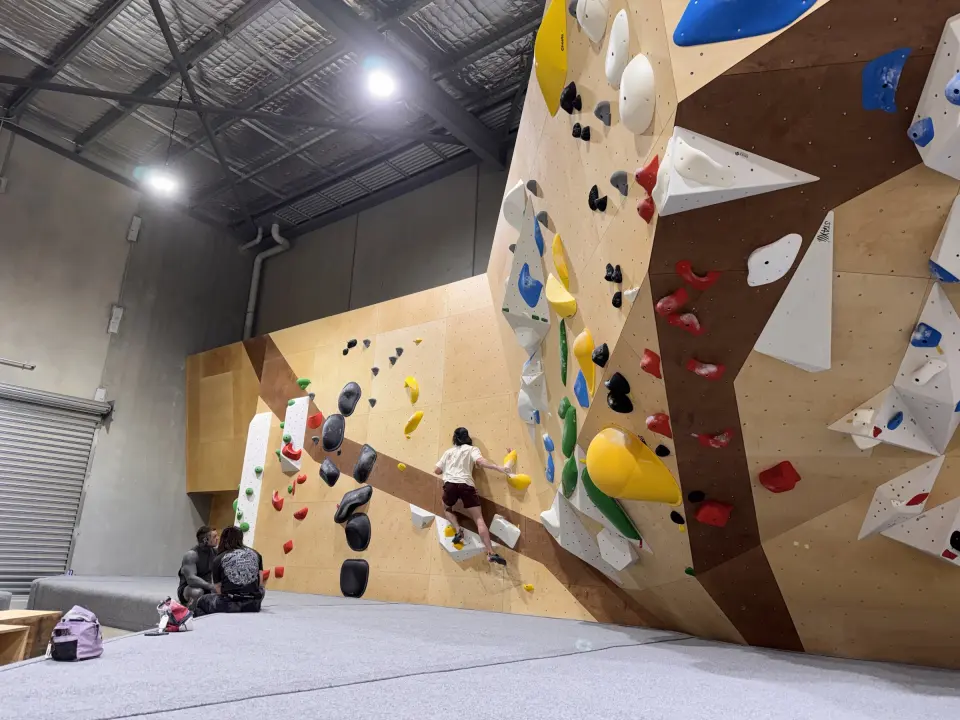 Bouldering walls with angled volumes and a roller door, above grey matting
