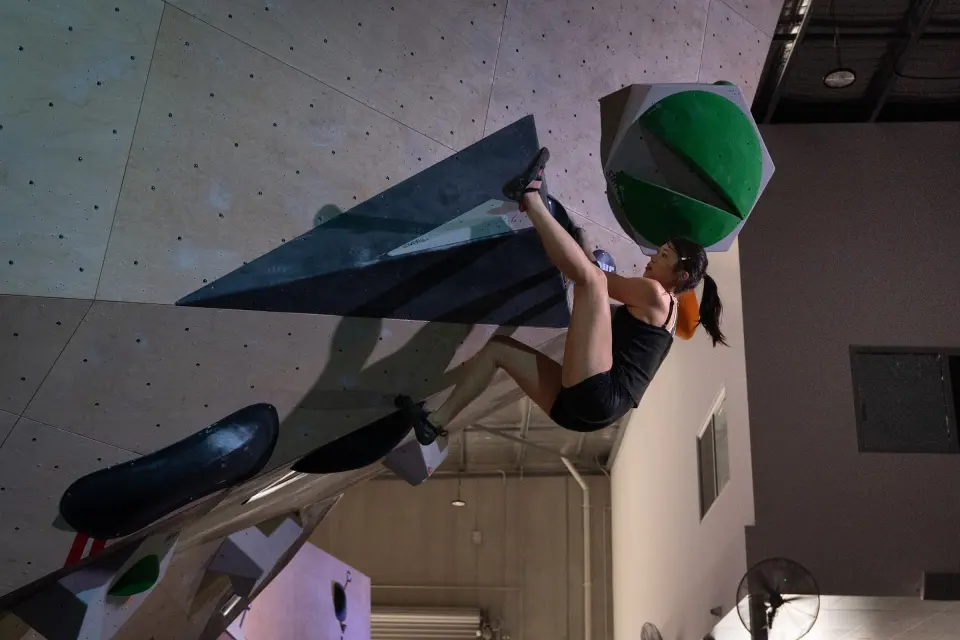 Climber hanging from a green volume in the steep overhang