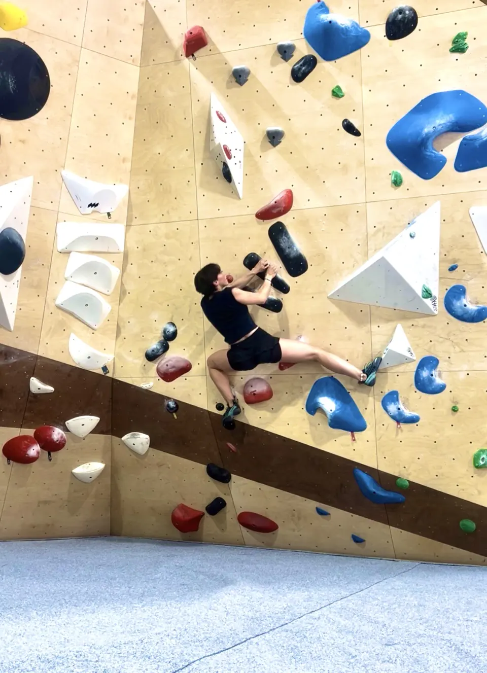 Climber spanning between holds on a vertical wall