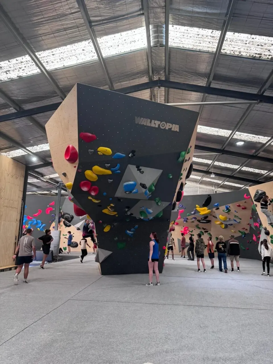 Climbers gathered around the tall Walltopia feature wall