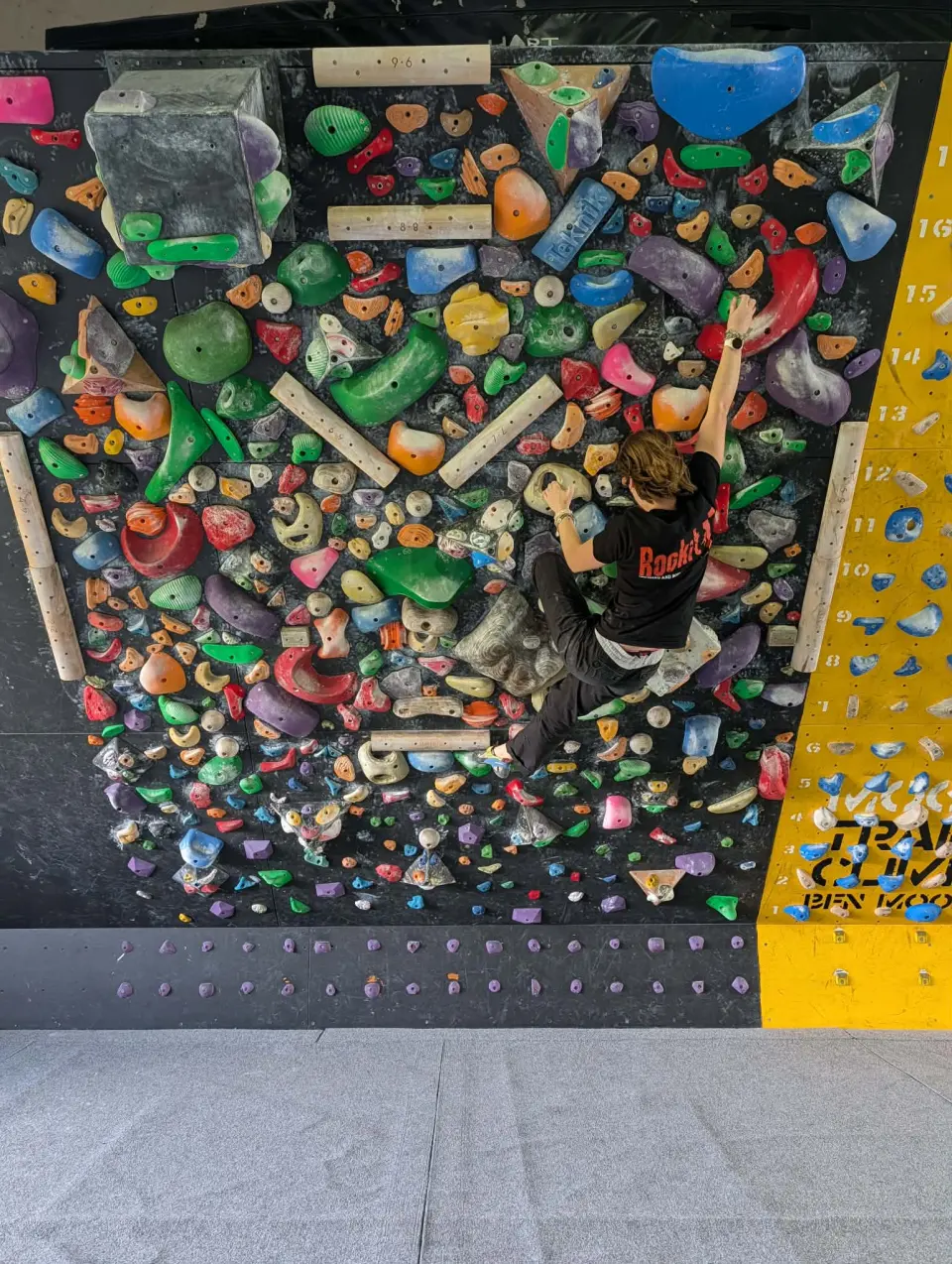 Climber on the spray wall, packed with holds