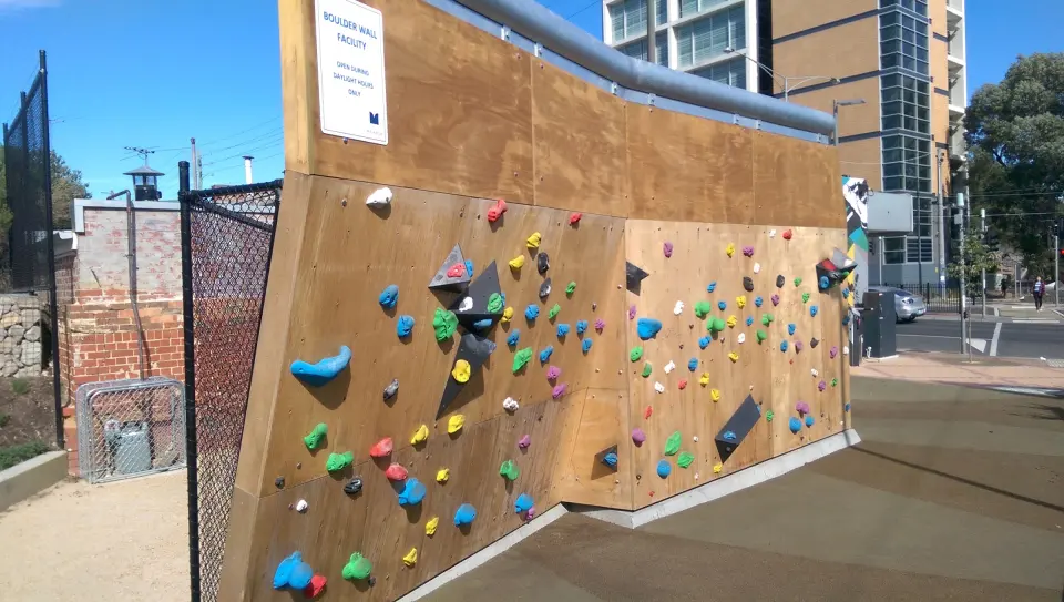 The bouldering wall with coloured holds above the rubber safety surface