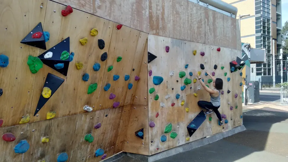 A climber on the right-hand section of the wall, with black triangular volumes on the left