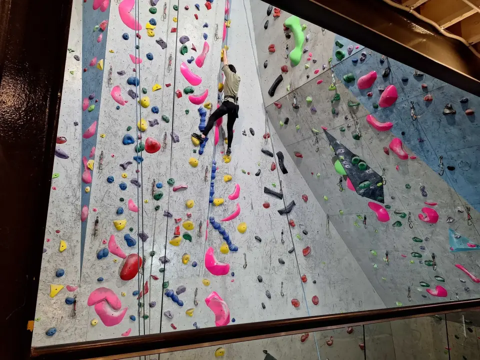 Climber high on the tall roped wall, seen from the balcony