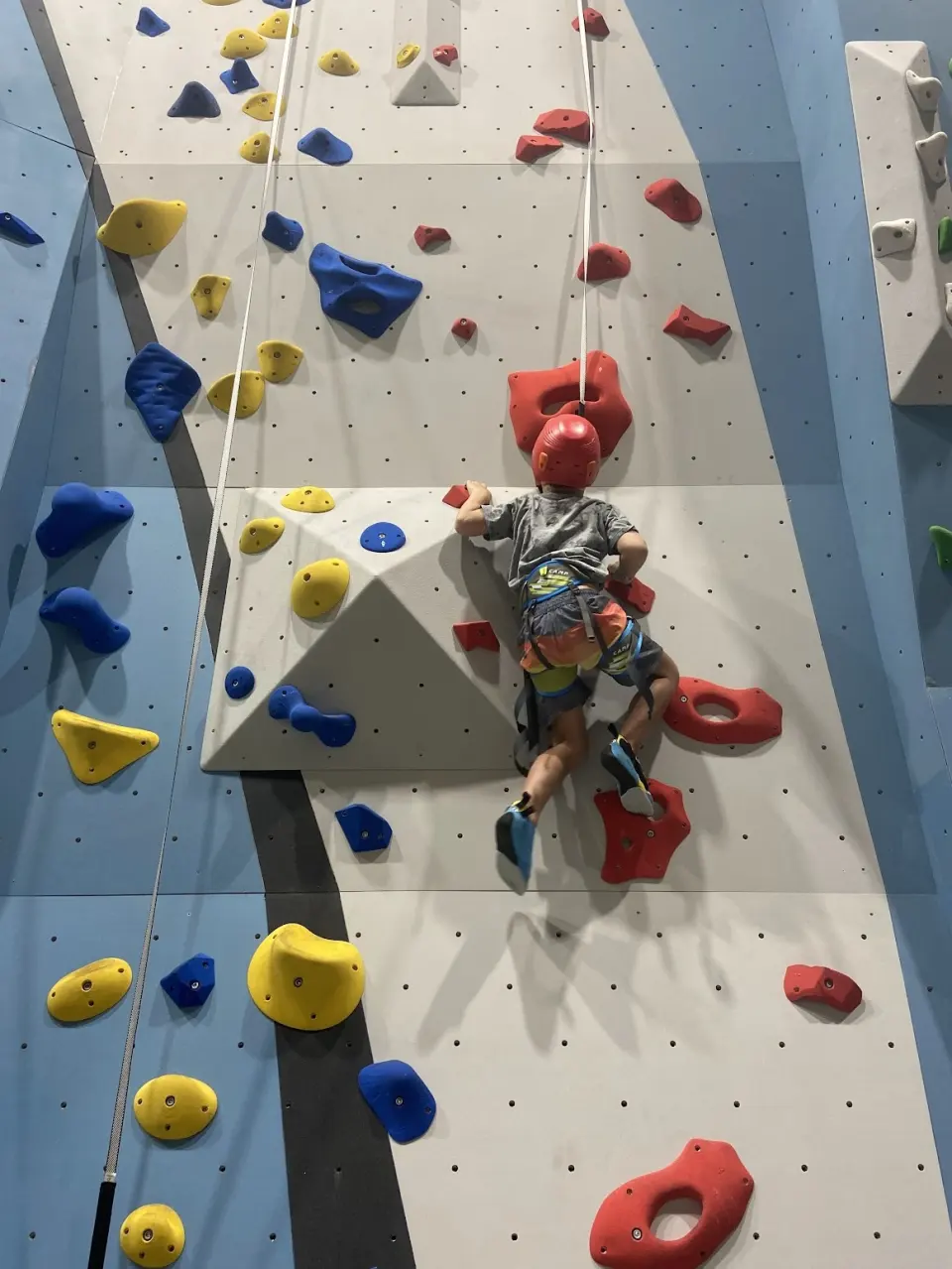 Climber passing the angled volume on an auto-belay lane