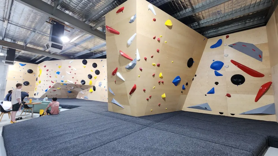 Plywood bouldering walls set with holds above deep matting