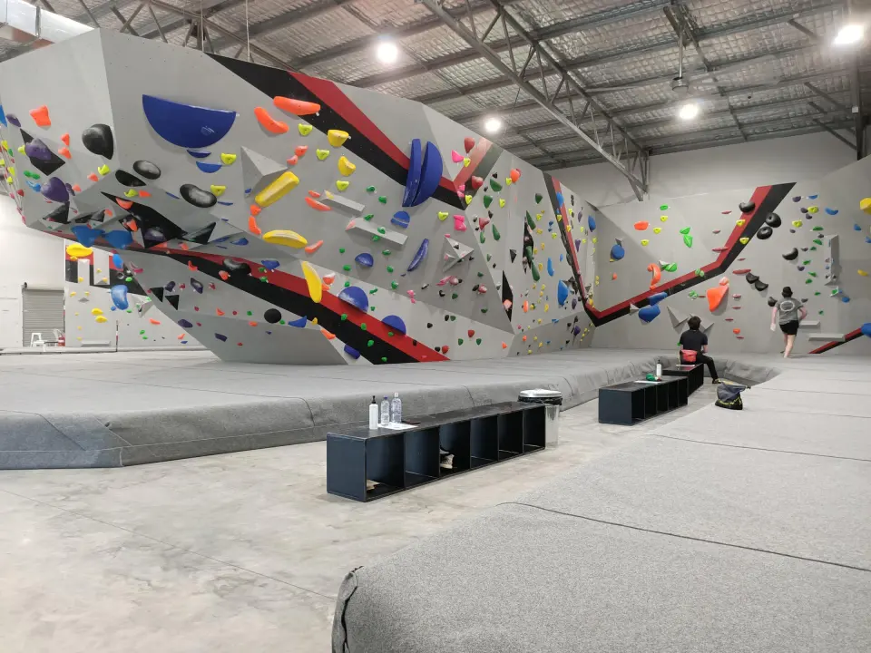 The bouldering hall at Pulse Climbing Maitland, with angled grey walls, red stripes and thick matting