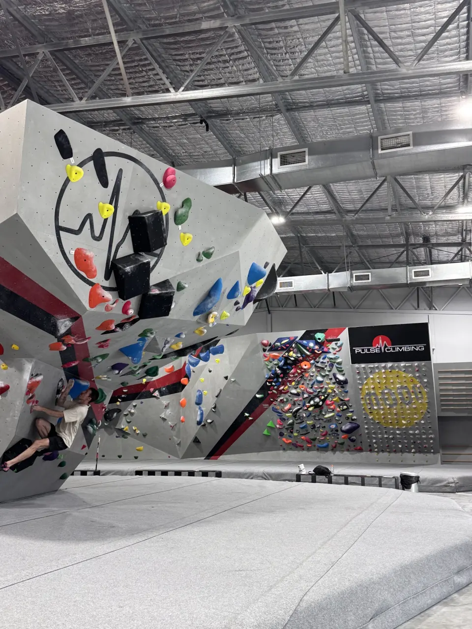 Overhanging wall with the Pulse heartbeat logo and a board of training holds behind