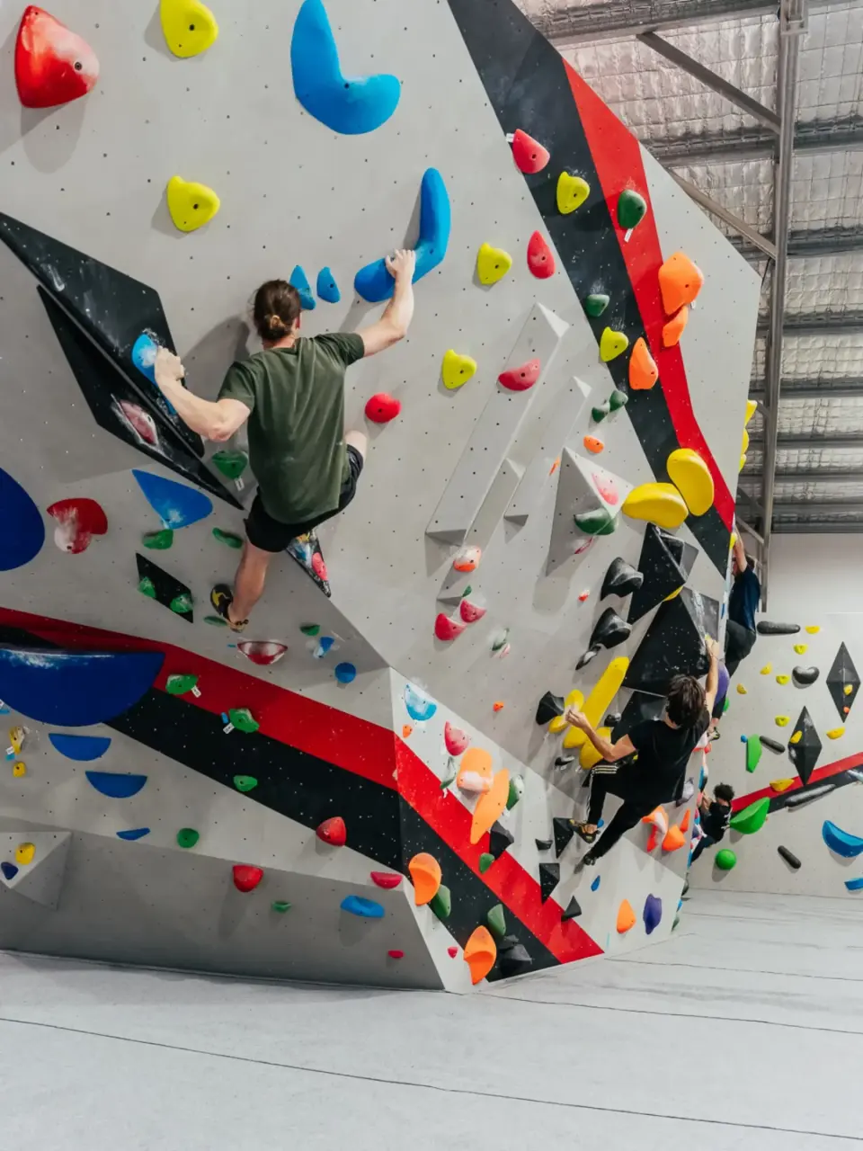 Climbers on the angled faces of the central bouldering wall