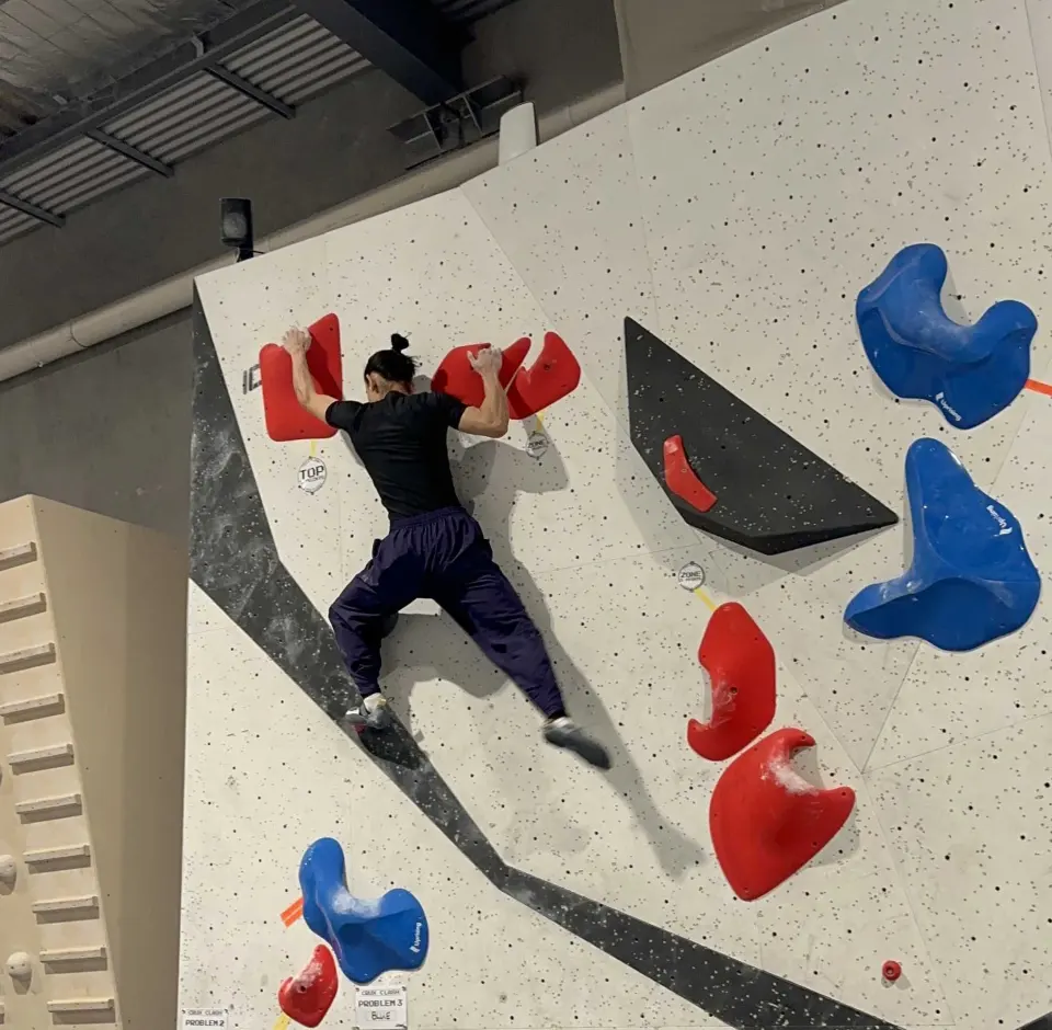 Climber on a slab with large red and blue holds