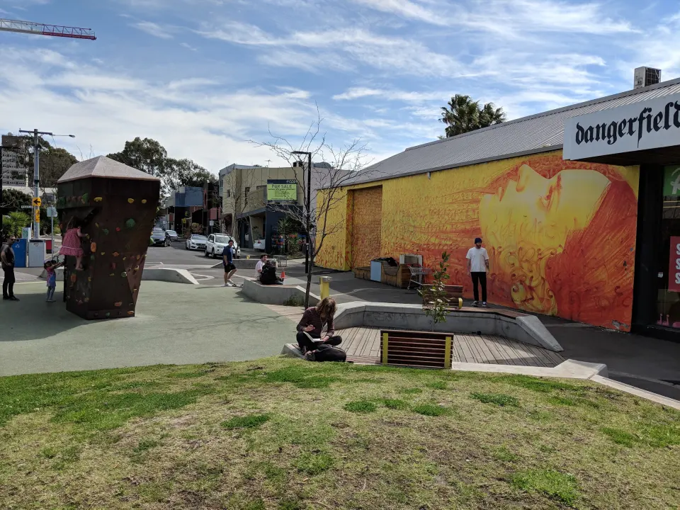 The bouldering wall at the Sydney Road end of Wilson Avenue, with lawn and seating