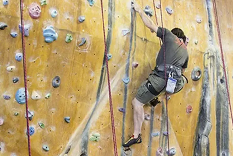Climber partway up the yellow rope wall