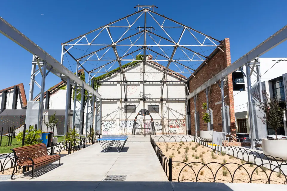 Steel roof frame of the old foundry over a table tennis table, benches and garden beds