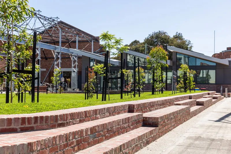 Brick terraces below the lawn, with steel frames and the old factory buildings behind