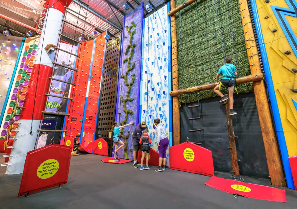 Clip 'n Climb hall with the Stairway to Heaven pole, coloured challenge walls and a log climb