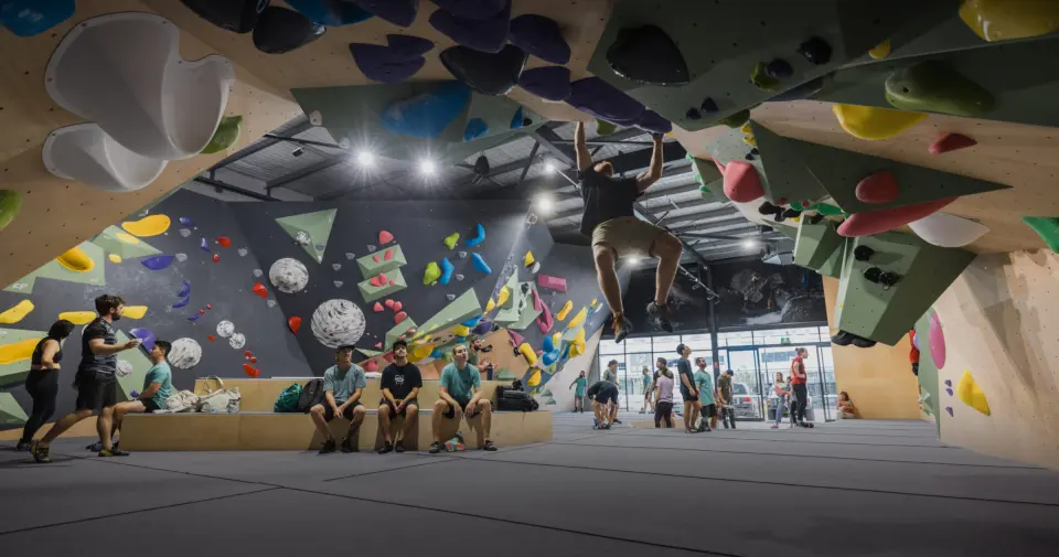 A climber hangs from the overhang at Cutloose in Upper Coomera while others rest on the benches below