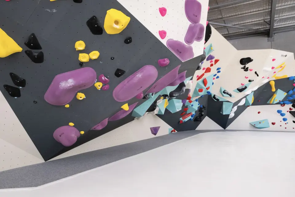 Bouldering walls with grey and white panels and purple, yellow and black holds at BlocHaus Mitchell, Canberra