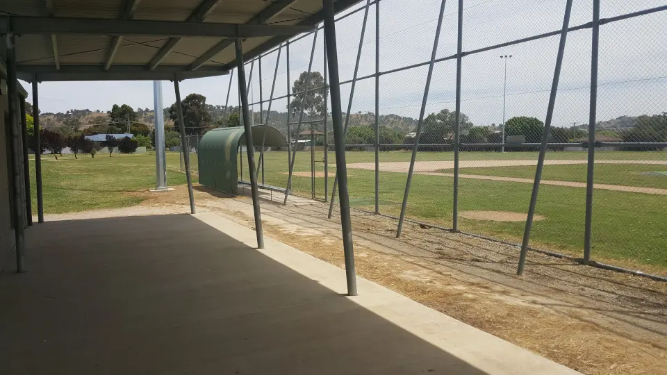 Covered dugout and backstop fence at the softball diamond in Gayview Park, with hills beyond