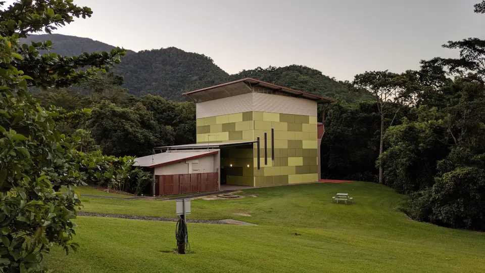 The tall climbing hall at The Northern Outlook, with rainforest-covered hills behind