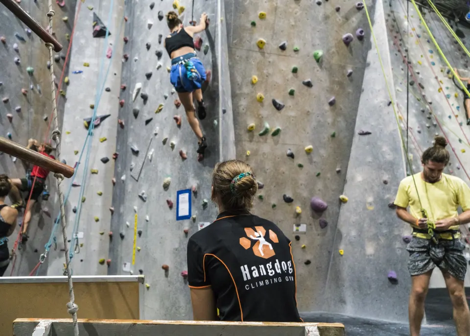Climbers on the roped walls of Hangdog Climbing Gym in Coniston, Wollongong, watched by a member of staff