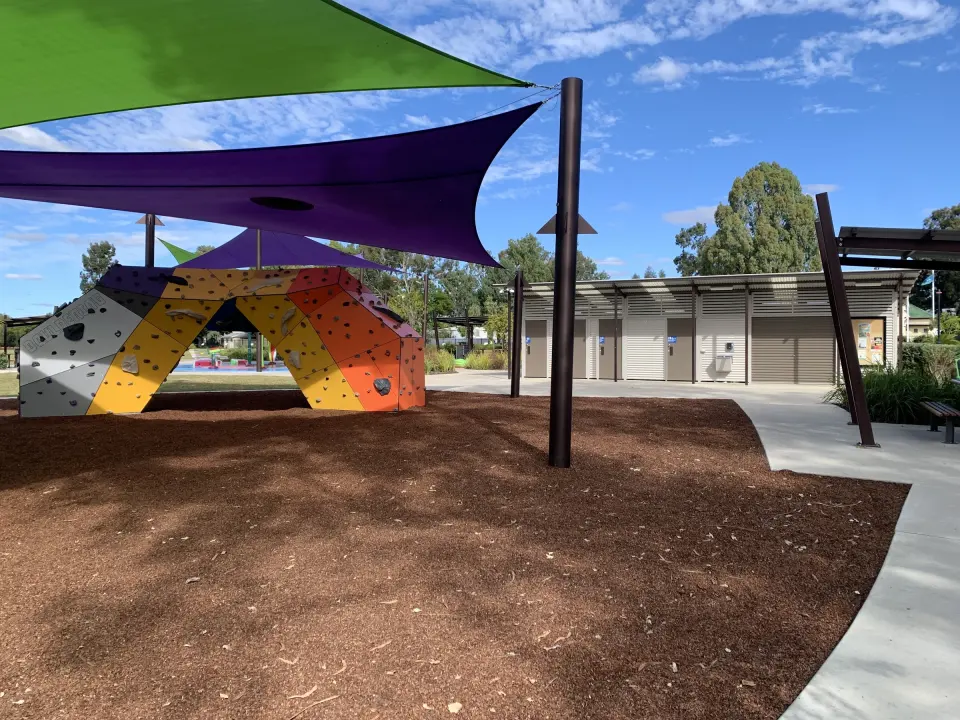 The bouldering arch under shade sails, with the park's toilet block behind