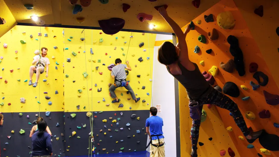 Climbers on the yellow and orange top-rope walls above the bouldering cave