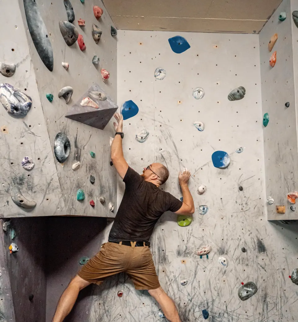 Climber bridging across the corner of the bouldering wall